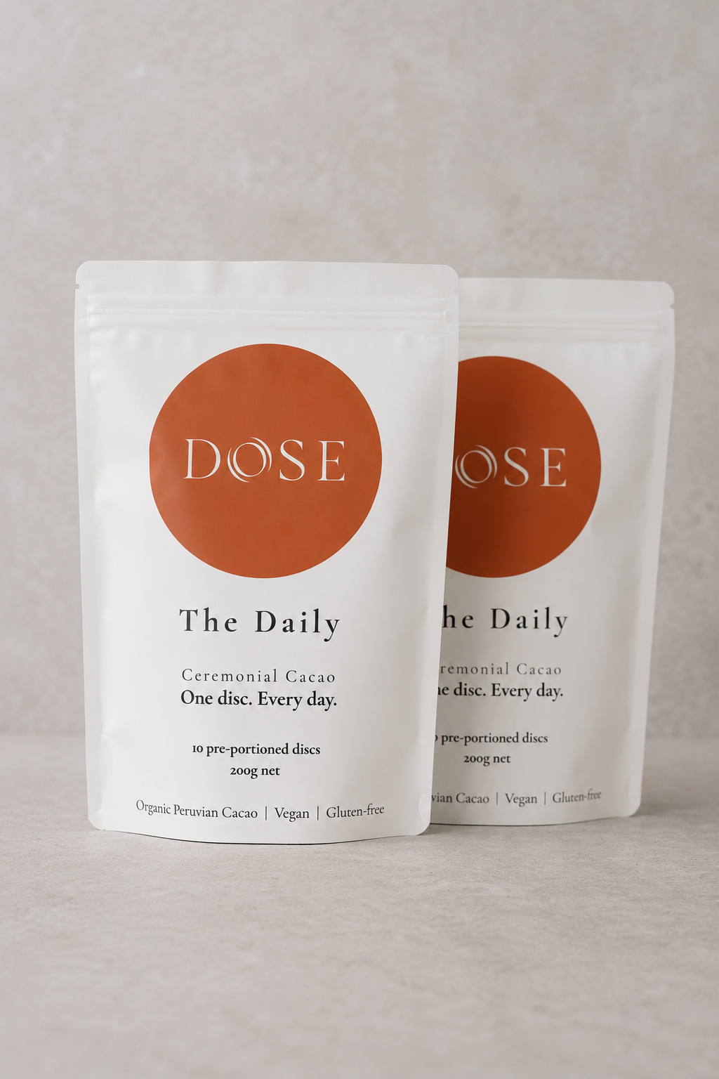 Two packages of 'Dose' The Daily Ceremonial Cacao on a gray background